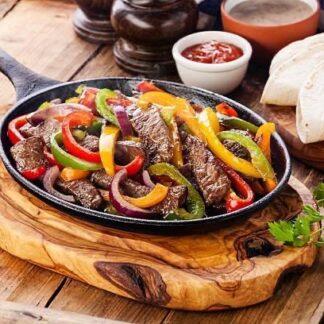 Fajitas de bœuf Servies avec des haricots frits (frijoles) et des tortillas de maïs. Minimum de 2 personnes